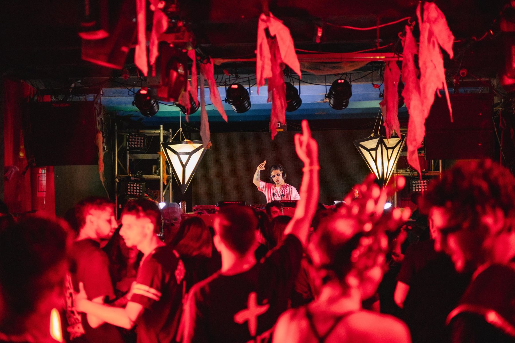 Diego Amaro en la cabina al fondo, saludando al público bajo luz roja, en Midas Club, Montevideo